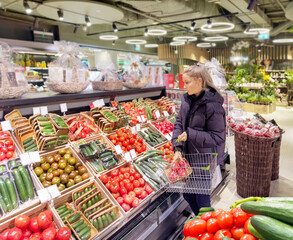 Woman buying vegetables(tomatoes and cucumbers) at the market