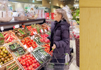 Woman buying vegetables(tomatoes and cucumbers) at the market