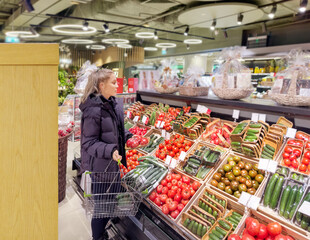 Woman buying vegetables(tomatoes and cucumbers) at the market