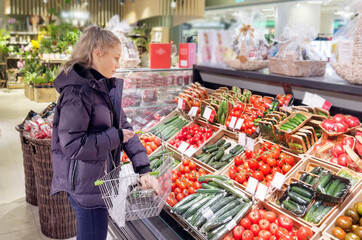 Woman buying vegetables(tomatoes and cucumbers) at the market