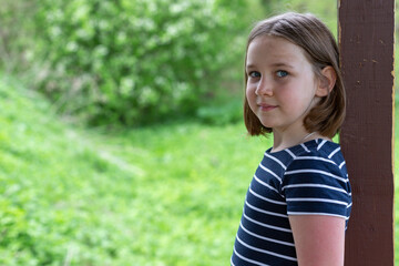 Fototapeta premium Cute schoolgirl girl on summer vacation in the fresh air surrounded by greenery