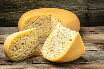 close up french hard cheese with holes emmentaler on a wooden background. farmer market. top view. place for text