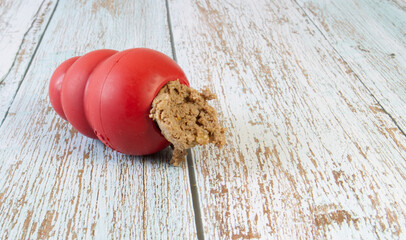 Red dog toy on a wooden background, used to entertain a dog or pet and for mental wear