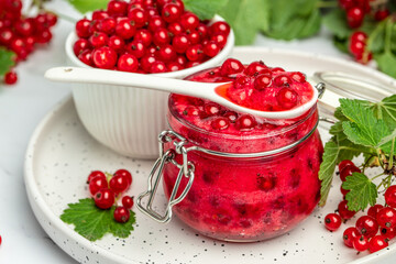 currant jam with fresh red currants on a light background. Homemade jam. Glass jar with red currant jam. Preserved berry