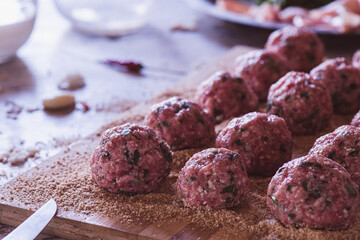 Close up of raw Meatballs on a wooden cutter with breadcrumbs
