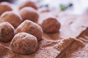 Raw homemade meatballs and breadcrumbs on a wooden cutter