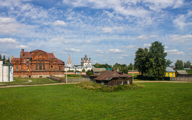Fototapeta na wymiar A beautiful urban landscape - the old town of Yuriev-polsky with ancient temples, a wooden hut and green trees on a sunny summer day and a space for copying
