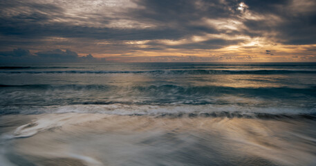 Fototapeta na wymiar Seascape with sea waves crashing in the coast at sunset. Idyllic sun down stormy cloudscape