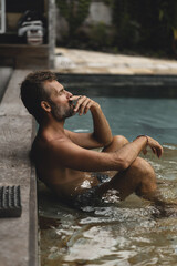 Man smokes a cigarette in a private villa by the pool.