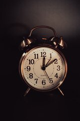 Copper color alarm clock on a dark background in vintage style