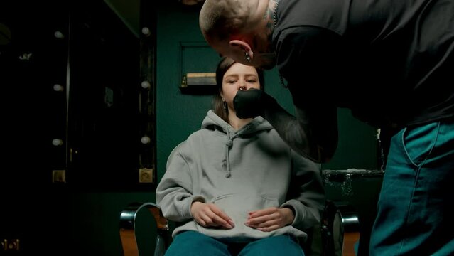 Piercing studio interior - piercing master makes piercing to girl septum nose piercing