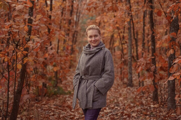 Beautiful smiling woman walking outdoors in autumn forest. Brown toned.