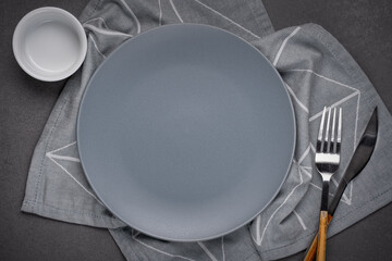 Empty gray matte plate and gray napkin on gray stone tabletop. Copy space for recipe, design or...