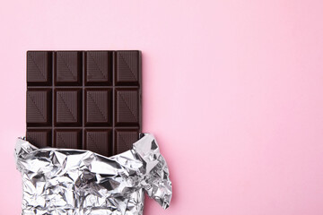 Tasty chocolate bar on pink background, top view. Space for text