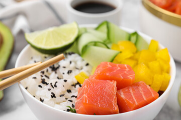 Delicious poke bowl with salmon, lime and vegetables on table, closeup