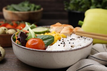 Delicious poke bowl with meat, rice, vegetables and greens on wooden table, closeup