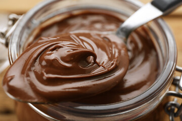 Glass jar and spoon of chocolate paste, closeup