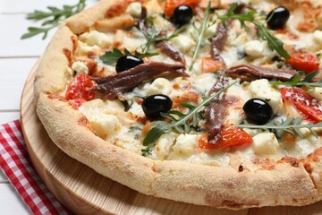 Tasty pizza with anchovies, arugula and olives on white wooden table, closeup