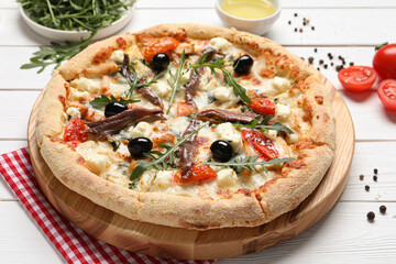 Tasty pizza with anchovies and ingredients on white wooden table