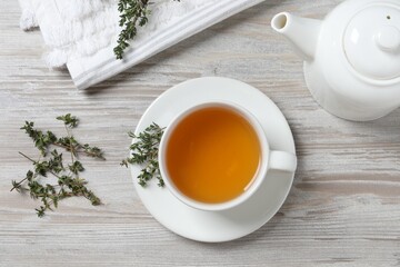 Obraz na płótnie Canvas Aromatic herbal tea with thyme on white wooden table, flat lay