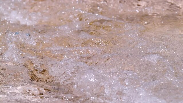 SLOW MOTION, CLOSE UP: Sparkling and splashing white water of mountain river. Spring water surface in beautiful wavy motion. Abstract view of small rapids in refreshing free flowing alpine river.