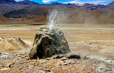 Close up geyser cone rock spitting hot water in dry arid barren valley - El Tatio geothermal field,...