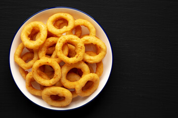 Homemade Breaded Onion Rings on a Plate on a black background, top view. Flat lay, overhead, from above. Copy space.