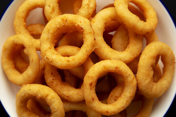 Homemade Breaded Onion Rings on a Plate on a black background, top view. Flat lay, overhead, from above. Close-up.