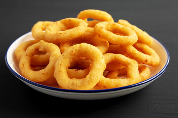 Homemade Breaded Onion Rings on a Plate on a black surface, side view. Close-up.