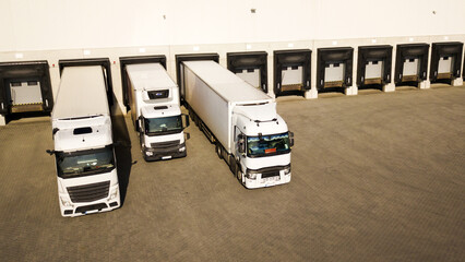 Aerial view of trucks loading in the distribution hub. Supply chain and warehouse logistics concept.