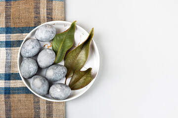 Grey Easter eggs with a sprig and a magnolia leaf on a grey background. Minimalism, copy space, flat lay
