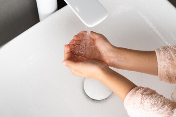 baby hygiene, little girl washes her hands under running water, baby's hands over the sink close-up
