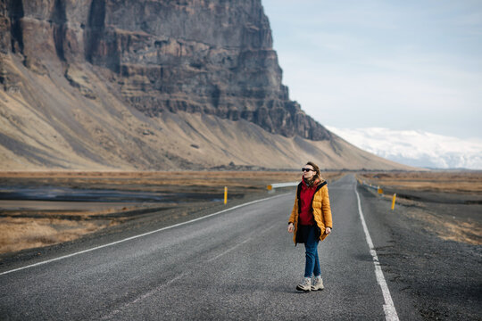 a girl in bright clothes walks along a winter road in Iceland