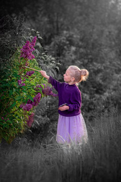 A girl in purple clothes paints nature in a black and white world