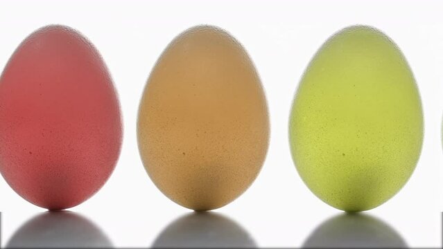 Multi-colored eggs move across the screen on a white background. Close-up of fresh, organic and healthy chicken eggs. Easter eggs clean background.