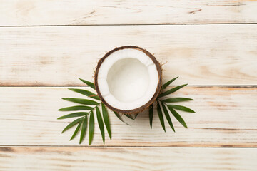 Fototapeta na wymiar Coconut with leaves on wooden background, top view