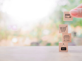 Close up hand arranging wooden block with online shopping and e-commerce icons set.