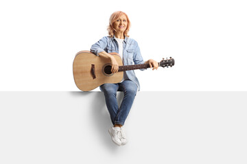 Full length portrait of a mature woman sitting on a panel with an acoustic guitar