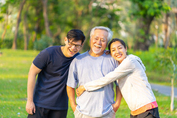 Portrait of Asian couple and elderly father jogging exercise together at park. Retired man with...