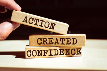 Wooden blocks with words 'Action created confidence'. Motivational reminder