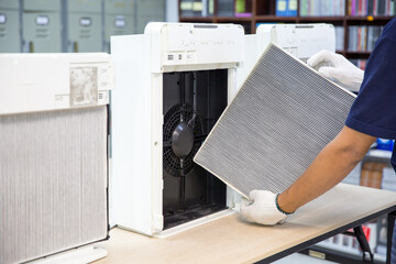 Air purifier technician open cover to fix and holding dirty and dusty air filter for removing and...