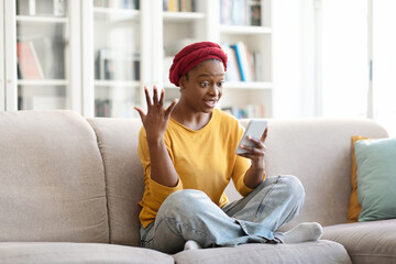 Amazed black woman using cell phone at home