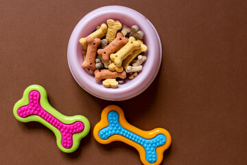 Close up of a Dog bones, bowl on brown background. Dog accessories, rubber toys. Minimalistic background.