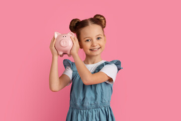 Portrait Of Cute Little Girl Holding Piggybank And Smiling At Camera