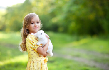 a little girl with white rabbit on her arms