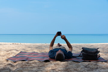 A man lying on a mat and using smartphone