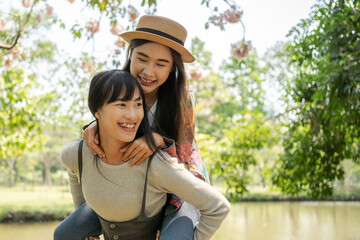 Young Asian girlfriends playing joyfully in a park. Holiday with a couple of females.