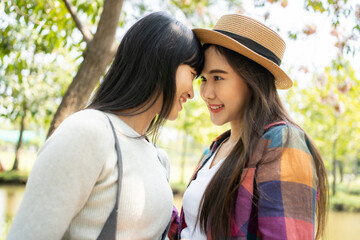 Fototapeta premium Young Asian girlfriends playing joyfully in a park. Holiday with a couple of females.