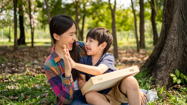 Happy harmonious Asian family park outdoors concept. Mother and son have activities teaching and learning together on holidays.