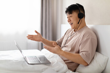 Happy chinese man have online party while staying in bed